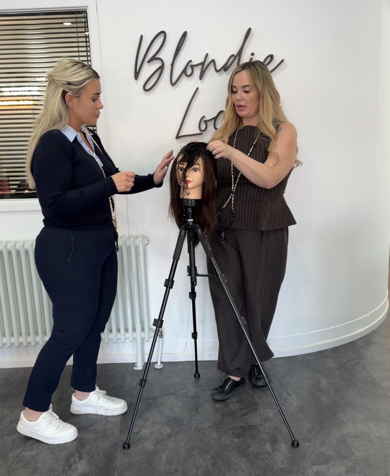 Nikki training a student with a mannequin head in the salon
