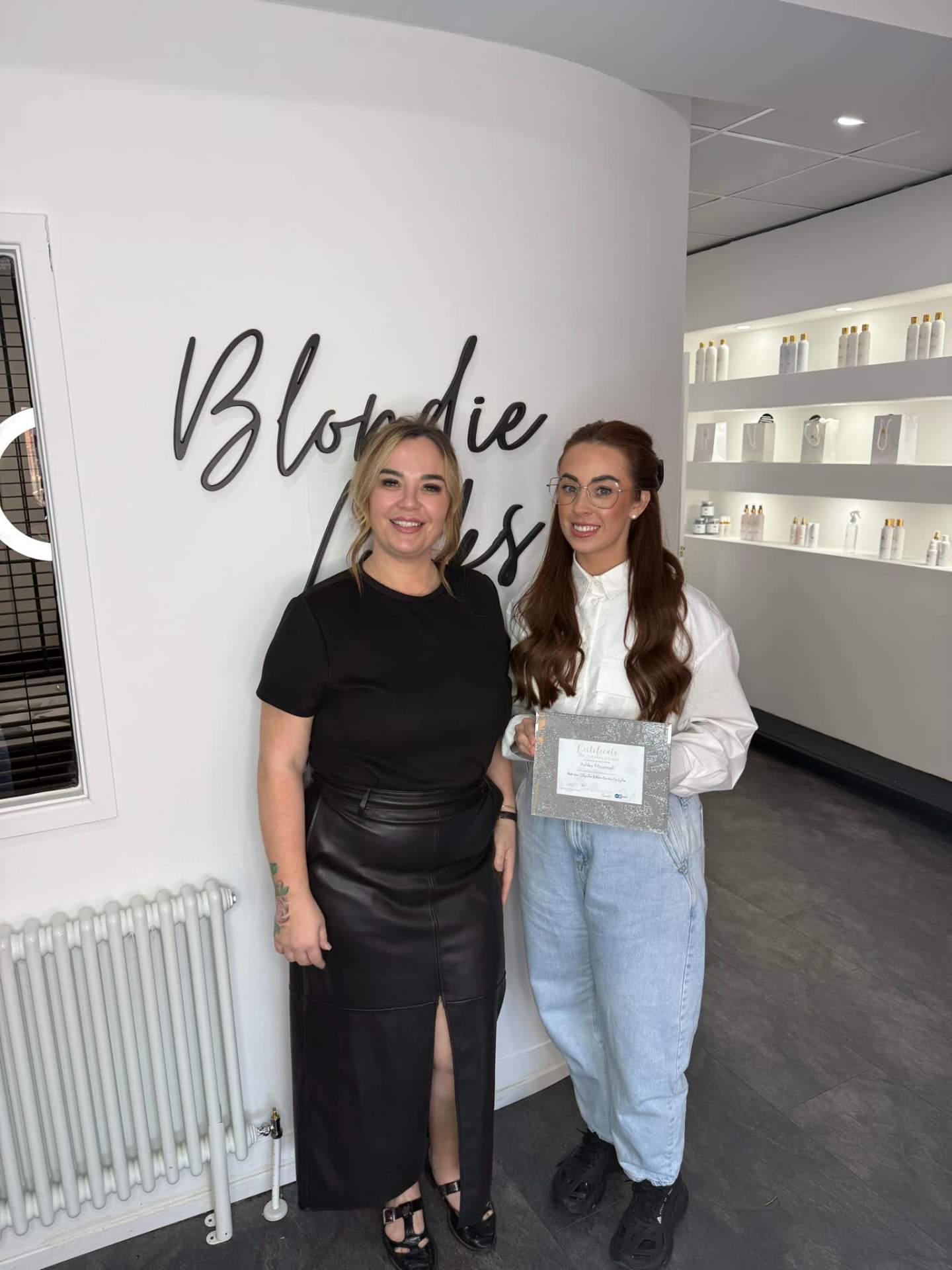 Nikki with a student holding a certificate in the salon
